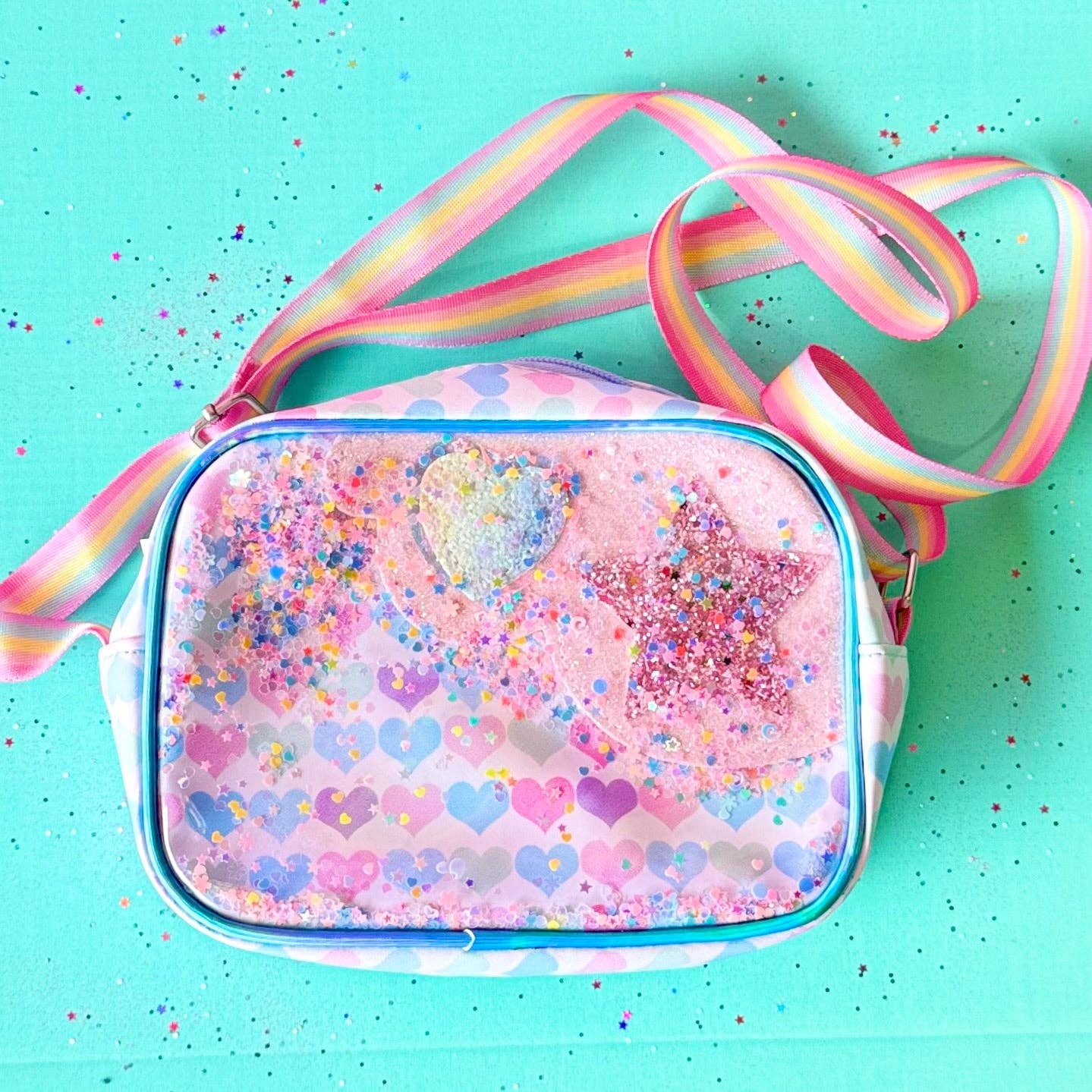 Pink heart-patterned bag with a colorful strap on a turquoise background