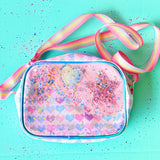 Pink heart-patterned bag with a colorful strap on a turquoise background